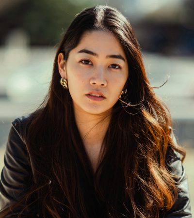 A portrait of a cool young and beautiful woman sitting in a park and looking at the camera with cool attitude.